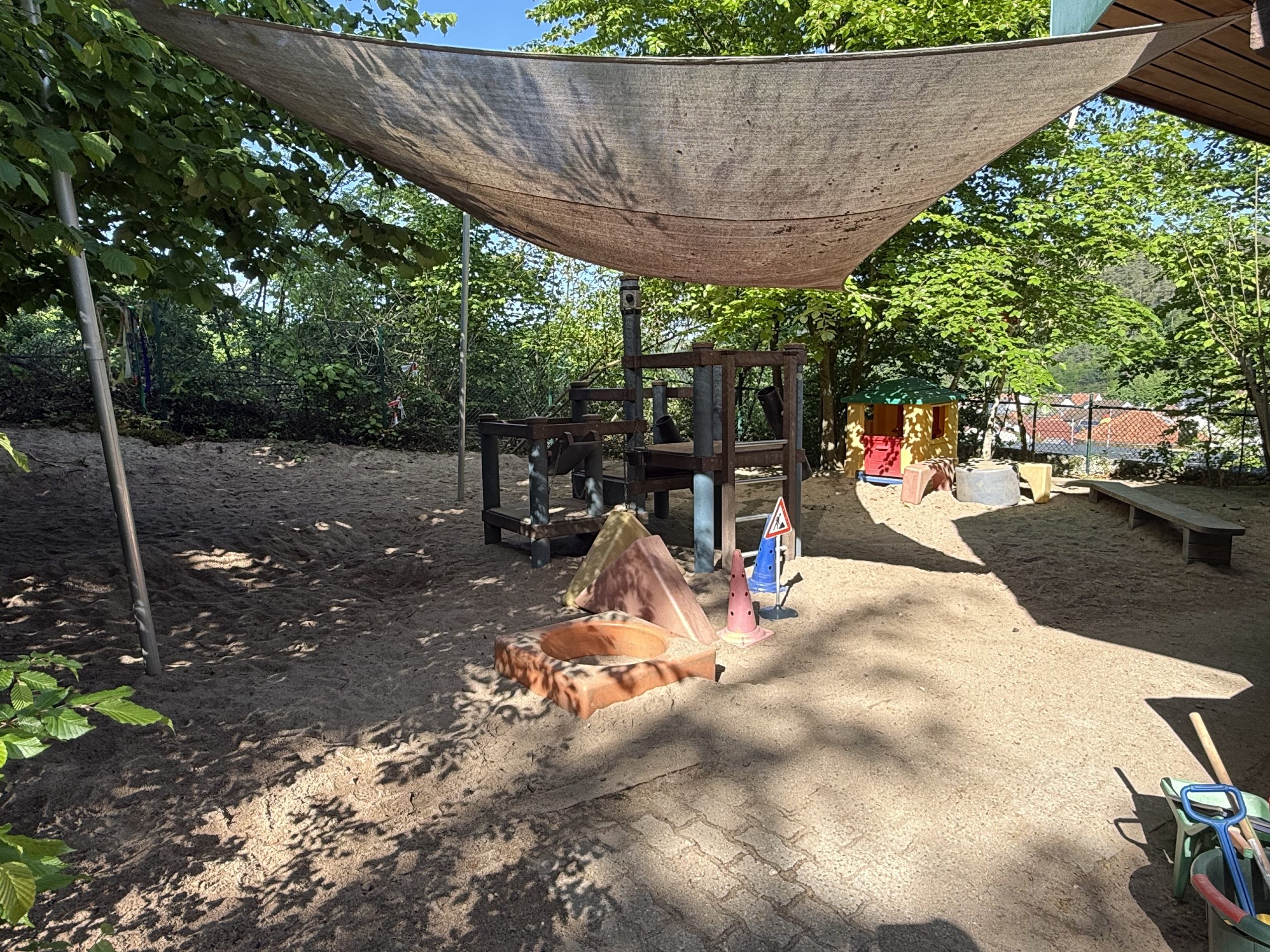 Unser Sandkasten mit Klettergerüst, großen Bausteinelementen und einem Spielhäuschen